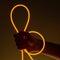 Flexible orange led tape neon in hand on black background