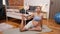 Flexible pregnant caucasian woman stretching her thigh while laying down on a gray yoga mat. Bedroom interior. Active
