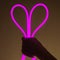 Flexible purple led tape neon in hand on black background