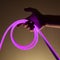 Flexible purple led tape neon in hand on black background