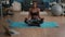 Flexible slim black woman sitting in lotus position on yoga map in living room