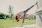 Flexible slim woman does stretching exercises outdoor stays in good physical shape dressed in cropped top and leggings stands on