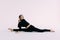 Flexible slim woman gymnast in black sportswear doing splits  on white background