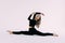 Flexible slim woman gymnast in black sportswear doing splits  on white background