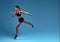 Flexible strong slim sportswoman running over blue background.