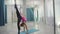 Flexible woman gymnast makes wheel and vertical split in gym.