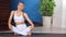 Flexible young girl relaxing turning body sitting in lotus position at modern yoga studio