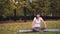 Flexible young lady is doing exercises for healthy spine sitting on yoga mat and moving back and body during individual