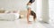 Flexible young woman doing handstand near wall practicing yoga, side view.