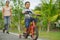 Flifestyle portrait of Asian Indonesian mother and young happy son at city park having fun together the kid learning bike riding