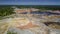 Flight above boundless clay quarry landscape with pond