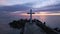 A flight around a Christian Holy cross early in the morning at sunrise. The large cross stands on the edge of a