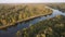 Flight in the evening over the river with densely overgrown banks.