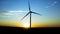 Flight by a large windmill with the sun setting in the background