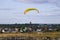 Flight of motor paraplan. a man flies on a bright colorful motoparaplane above the village, field and construction site.