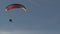 Flight of a motorized paraglider against a blue sky.