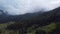 A flight from mountain meadows over green forests, under a misty mountain after rain.