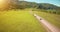 Flight over cars on a winding road in the hills and meadow. Rural highway below.