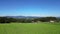 Flight over a green field with a view of a forest, in the background the Bavarian Forest