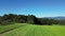 Flight over a green field with a view of a forest, in the background the Bavarian Forest