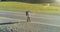 Flight over hitchhiker tourist walking on asphalt road. Huge rural valley at summer day. Backpack hiking guy.