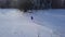 Flight over the lonely tourist girl walking along the top of a mountain covered with snow. Clear frosty weather