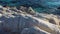 Flight over the massive white rocks on the sea coast and turquoise clear sea splashing. Aerial view