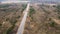 Flight over a narrow asphalt road with a passing truck outside the city.