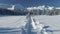 Flight over a snowy country road on a sunny day overlooking the mountains