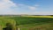 Flight over spring landscape in Central Europe, green fields and meadows and yellow meat of oilseed rape, agricultural and village