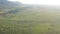 Flight over vast fields next to large hills