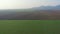 Flight over a vast wheat field under a couple of hills