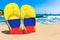 Flip flops with Colombian flag on the beach. Colombia resorts, vacation, tours, travel packages concept. 3D rendering