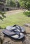 Flip-flops sandal over rocks beside grass recreation area of Acebo natural swimming pool