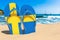 Flip flops with Swedish flag on the beach. Sweden resorts, vacation, tours, travel packages concept. 3D rendering