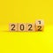 Flip over wooden cube block with new year 2022 on yellow background