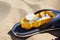 Flipflop in the sand with sand mold, shells, stones and butterfly