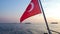 Flipped Turkish national red flag waving in wind against sunset on ferry