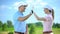 Flirting female and male golf players giving high-five after game, sympathy