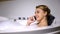 Flirty woman talking phone, enjoying bath with foam bubbles, conversation