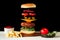 Floating beef burger. Tasty grilled meat with flying food ingredients on a black and white background with homemade ketchup