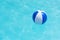 Floating blue and white beachball in swimming pool.