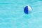 Floating blue and white beachball in swimming pool.