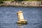 Floating bouy in lake saying Keep Right bobbing on rough water with relfection and blurred shore and rip rap in distance