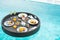 Floating Breakfast tray in swimming pool at luxury hotel or tropical resort villa, fruits; mango, watermelon dragon and passion