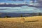 Floating clouds above a hay field with straw bales and Lake Mjosa in the distance in Toten, Norway