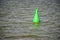 Floating green buoy on blue water