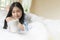 Floating posture uses the mind of Asian young woman lying holding a cup of coffee on white bed in morning