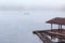Floating raft house on river with foggy and long tail boat on background.