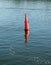 Floating red navigational buoy on blue water of Dnipro River.